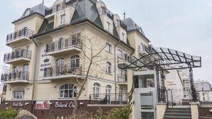 Un edificio de varios pisos con balcones, un letrero que dice 'Bilard Club' y un anuncio de 'Drink Bar'.