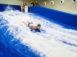 Una persona deslizándose por un tobogán acuático en una piscina.