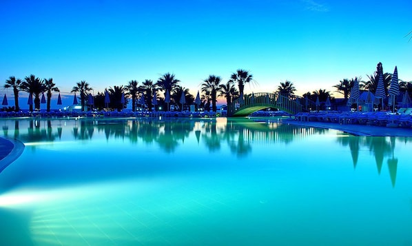 Alberca techada, alberca al aire libre y sombrillas en la alberca