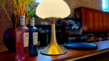 Un comptoir de bar avec deux bouteilles de FLUÈRE, une lampe de couleur dorée et une plante en pot.