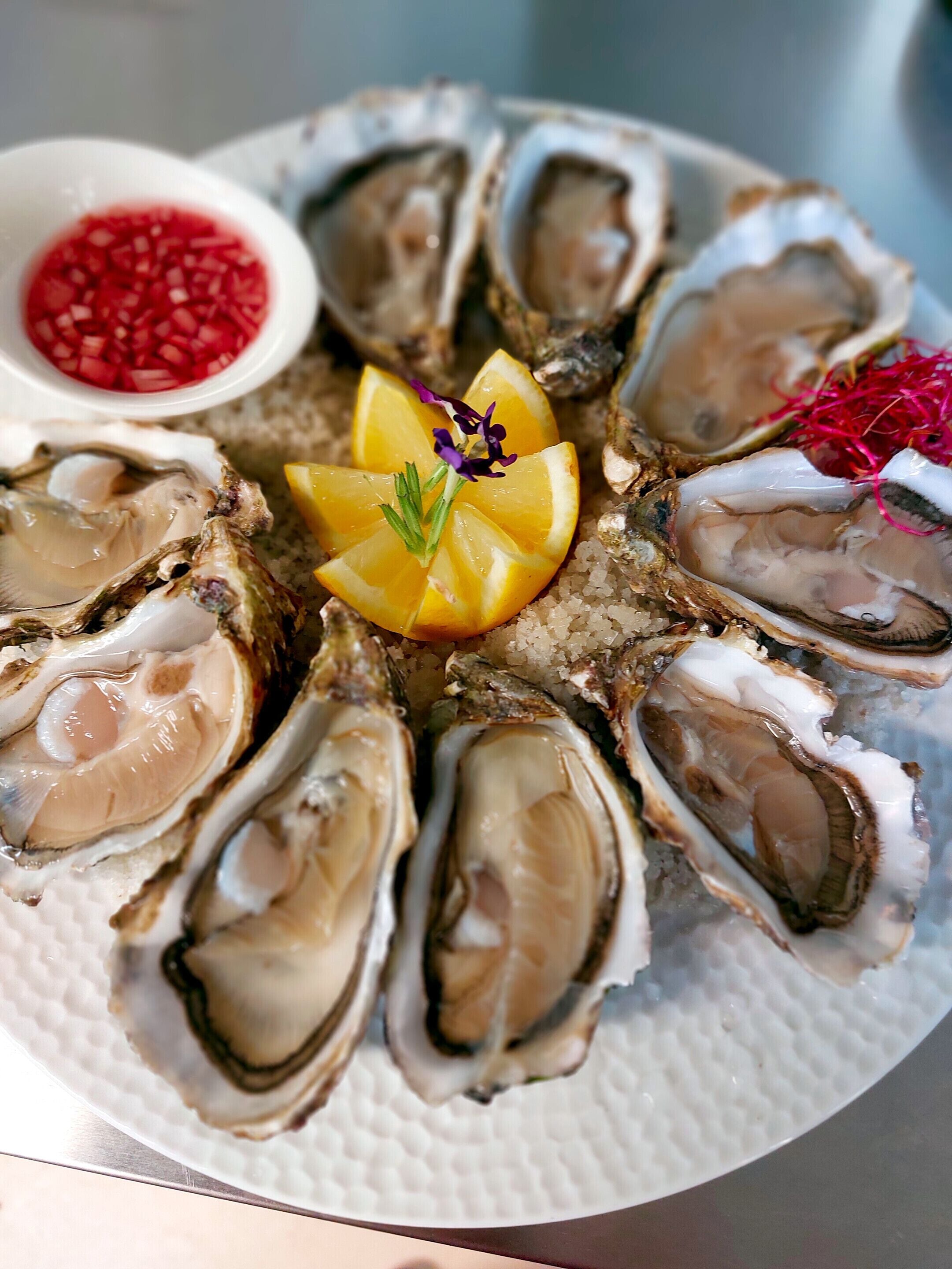 Un plato de ostras con rodajas de limón y guarniciones.