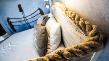 A bed with a thick rope headboard, a metal frame, and several pillows.