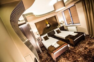 Quarto de hotel com duas camas, um espelho grande, um relógio e um radiador.