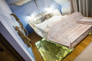 Quarto com cama, luminária na parede e um pequeno aquário.