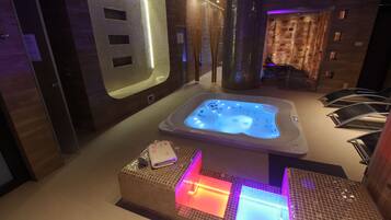 Un espace bien-être comprenant un jacuzzi, une table de massage et un sol carrelé.