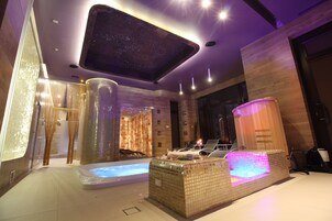 Uma área de spa moderna com hidromassagem, mesa de massagem e sauna a vapor.