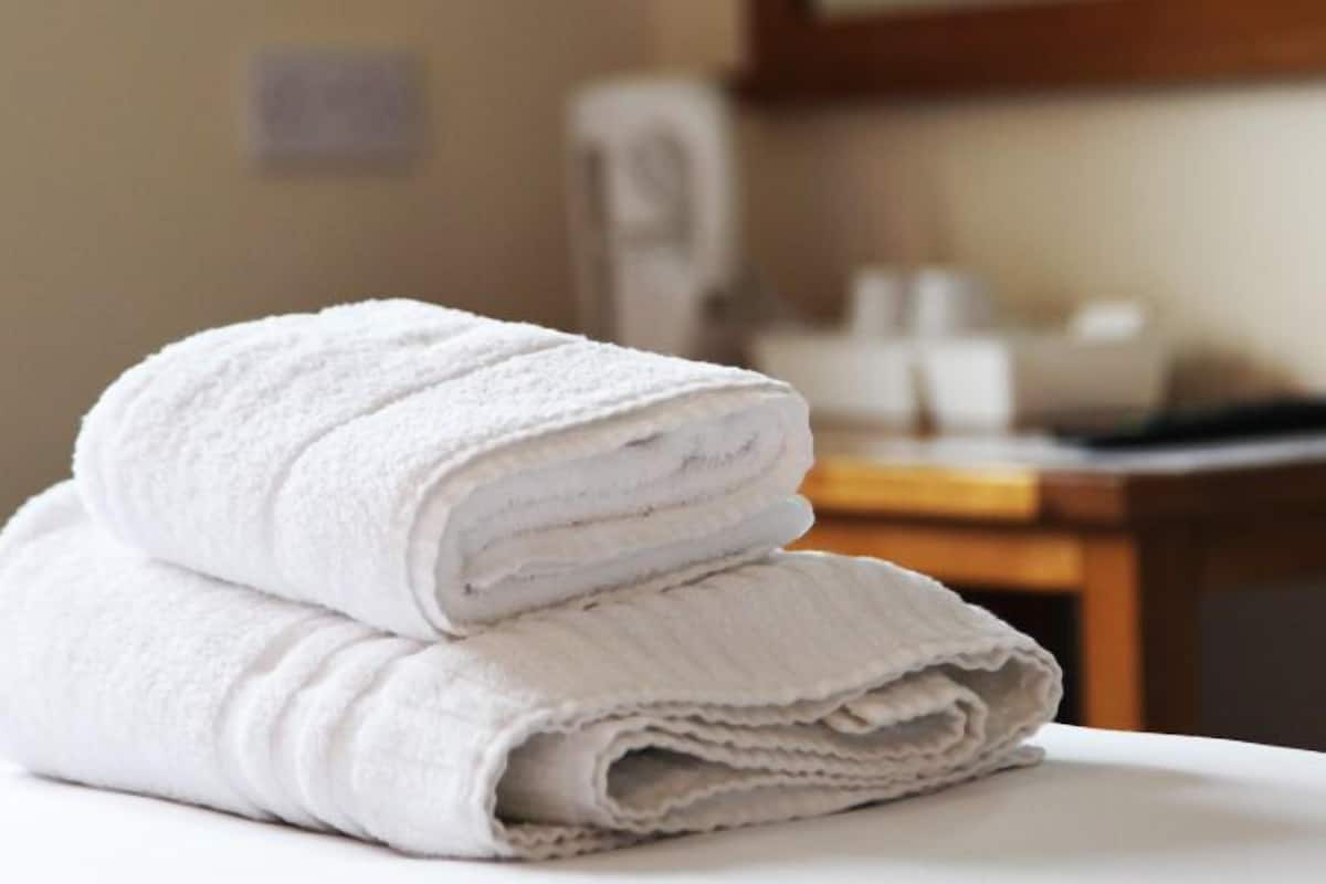 A stack of white towels on a white surface in a hotel room.