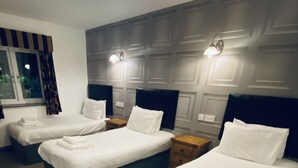 A hotel room with three neatly made beds, each with white linens and pillows, and a window with curtains. - Hockley House (Solihull)