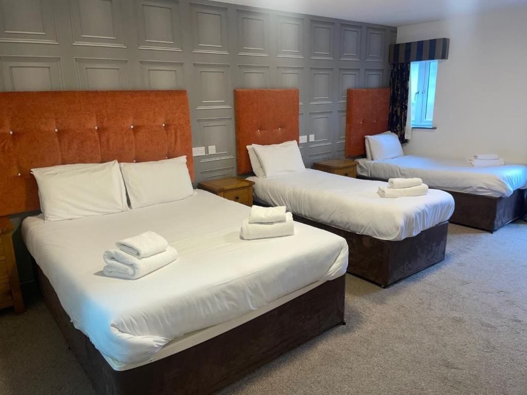 A hotel room with three beds, each with a headboard and white bedding.