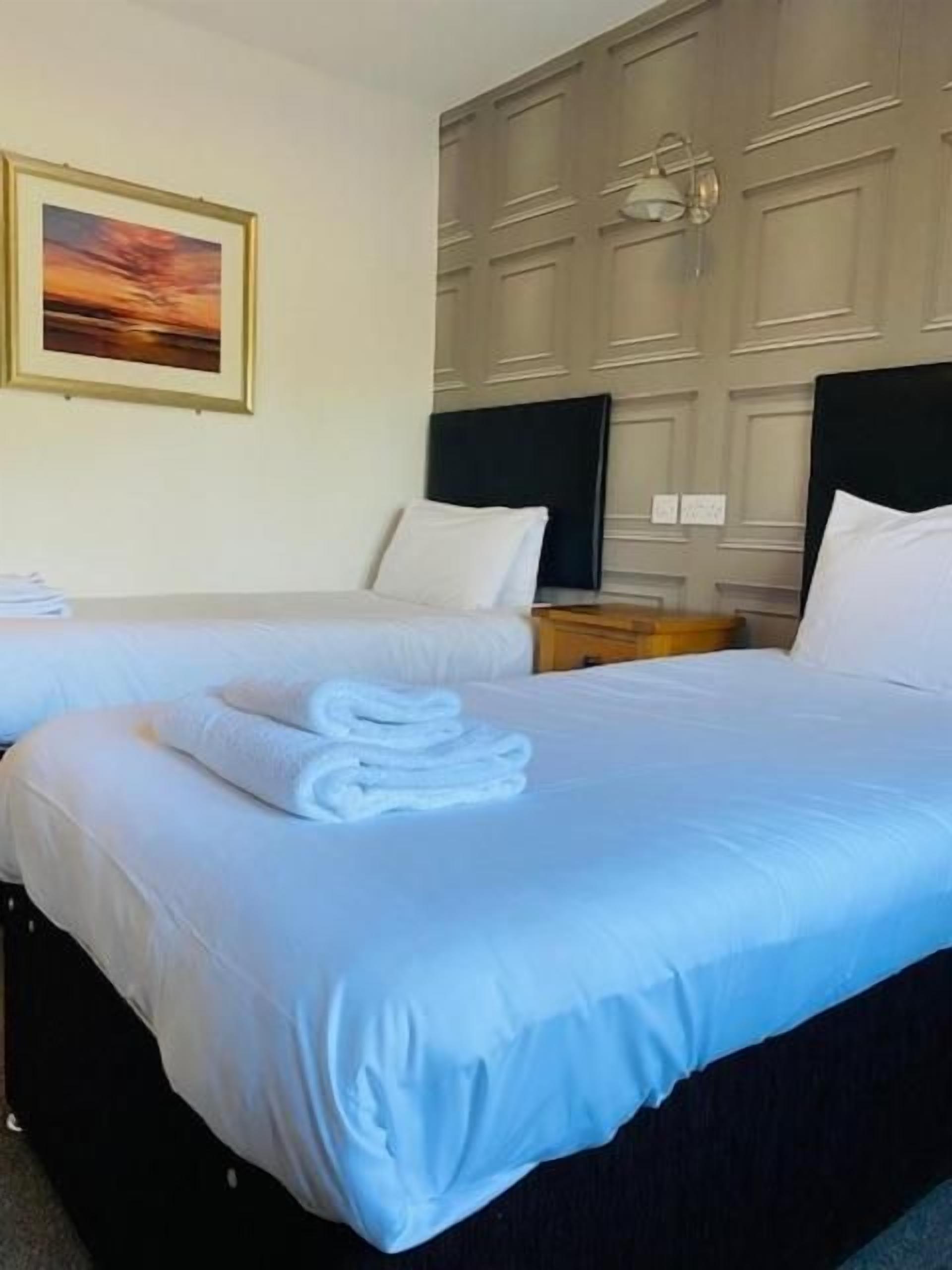 Habitación de hotel con dos camas, un cuadro en la pared y un cabecero de madera.
