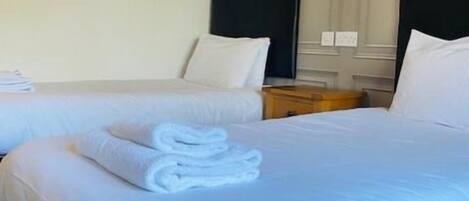 Habitación de hotel con dos camas, un cuadro en la pared y un cabecero de madera.
