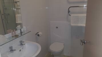 Une salle de bain avec une douche à parois de verre, un lavabo blanc et des toilettes.