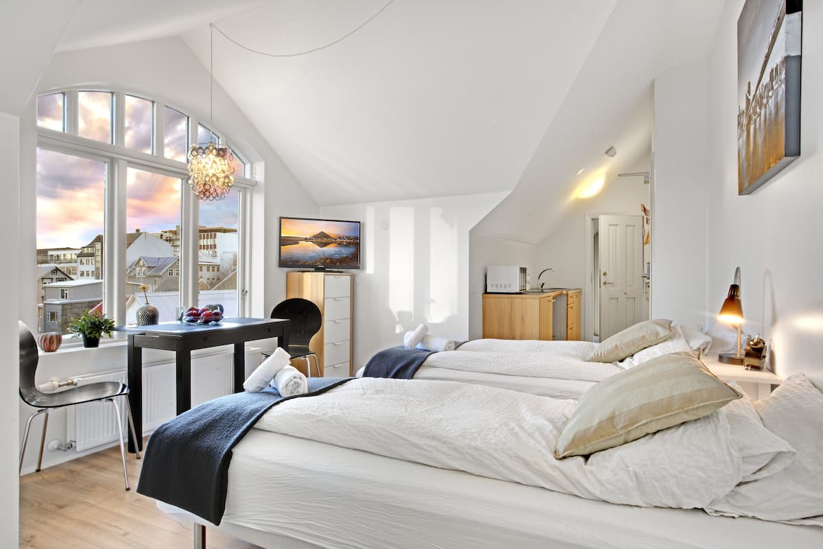 Quarto moderno com duas camas, uma mesa e uma cadeira.