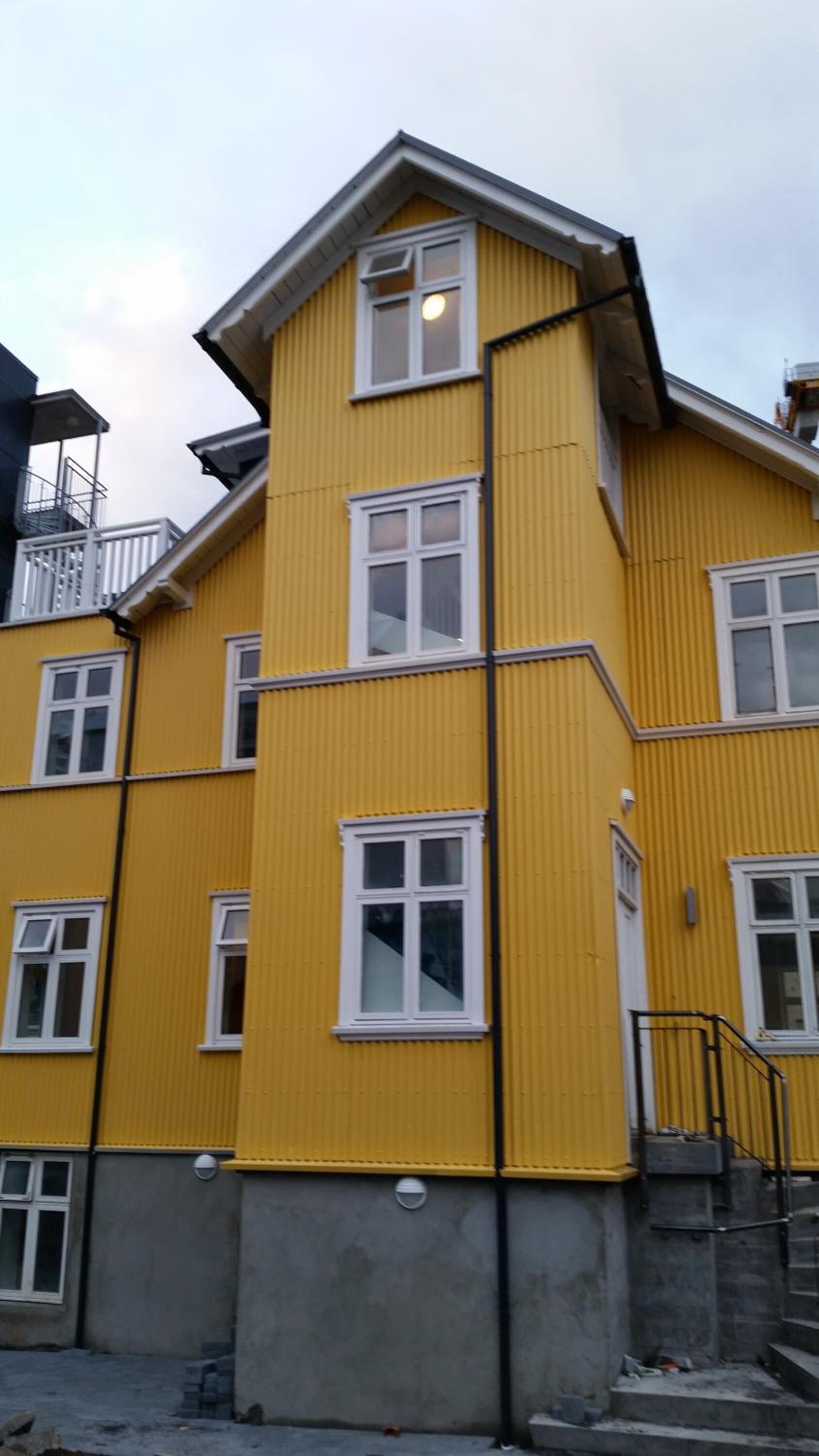 A yellow multi-story building with white-framed windows and a visible staircase leading to an upper floor.