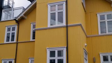 A yellow multi-story building with white-framed windows and a visible staircase leading to an upper floor.