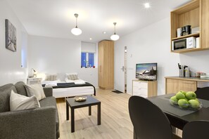 Una habitación moderna y luminosa con una cama, un sofá, una mesa de comedor con manzanas y un televisor.