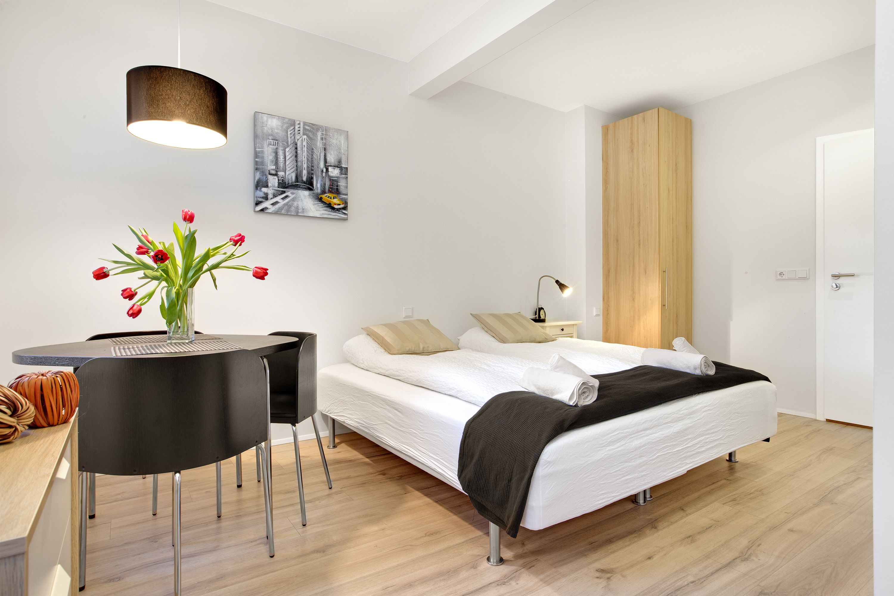 Ein modernes Schlafzimmer mit Bett, Nachttisch, Lampe und einem Bild an der Wand.