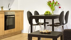 A modern kitchen with wooden cabinets, a built-in oven, and a dining area with a table and chairs. - Alfred's Studios (Reykjavik)