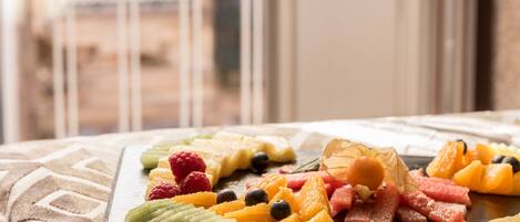 A fruit platter on a wooden board with various fruits and a decorative leaf.