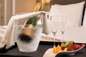 Una bottiglia di champagne in un secchio con ghiaccio, due bicchieri vuoti e un piatto di frutta.
