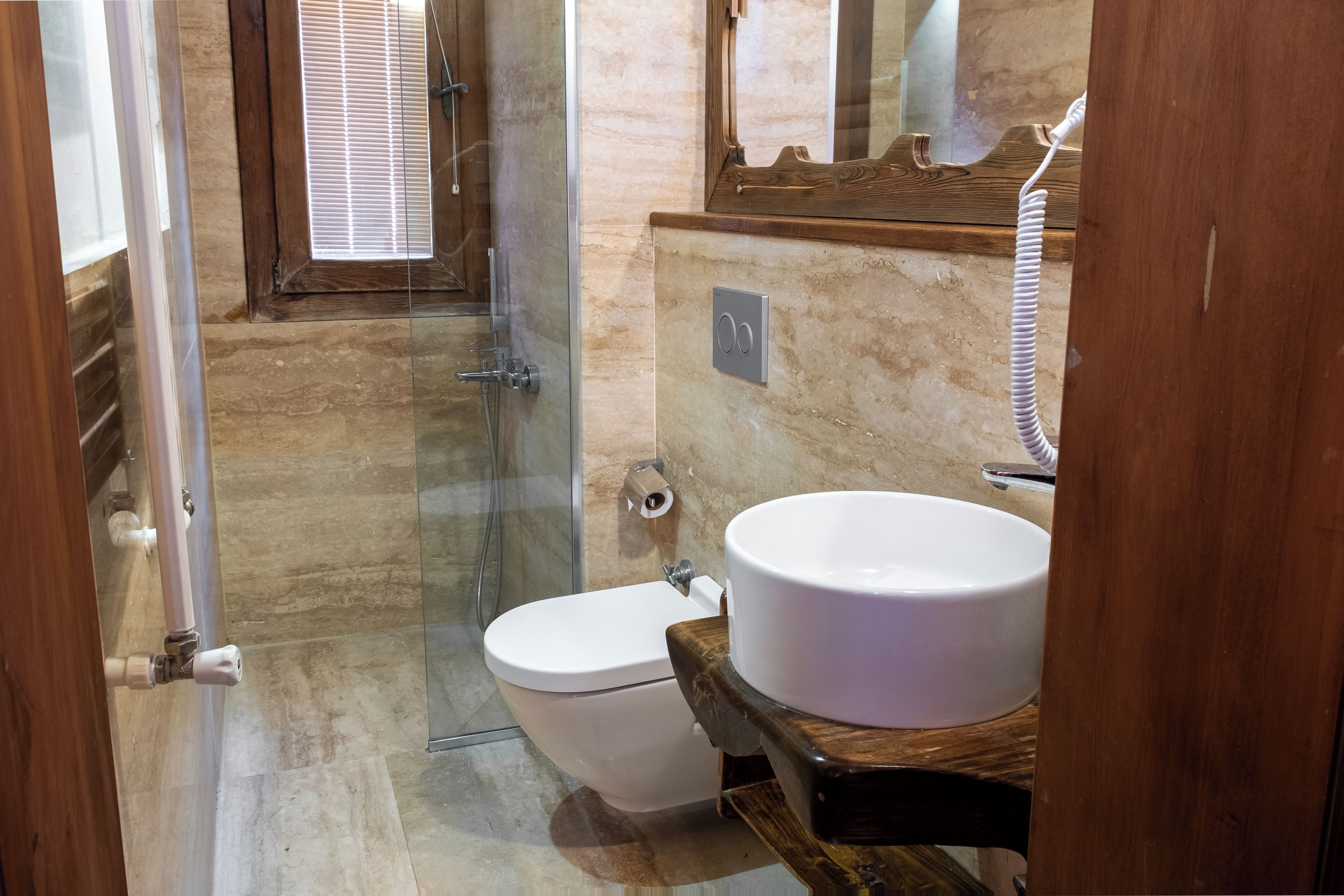 A bathroom with a glass shower enclosure, a toilet, and a sink with a wooden countertop.