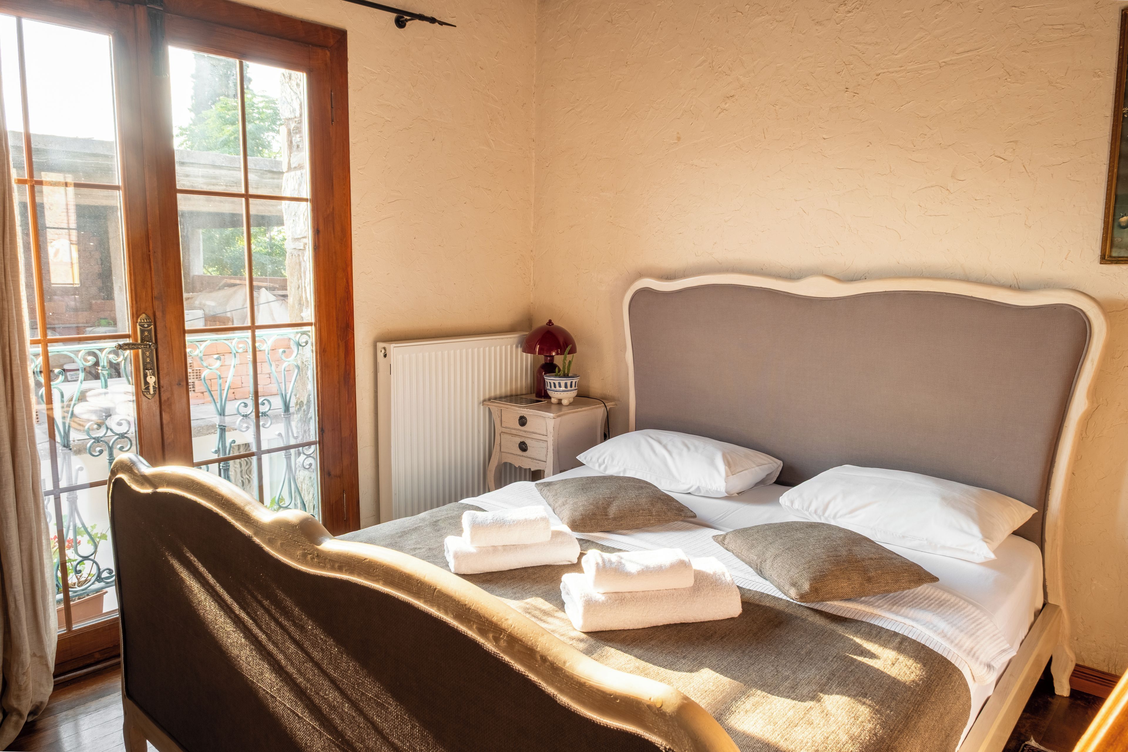 A bedroom with a bed, bedside table, and a view of the outside.