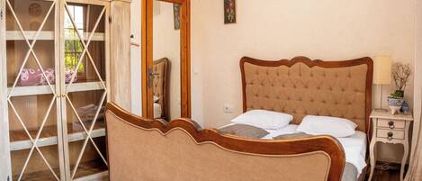 A bedroom with a wooden bed, a nightstand, an air conditioning unit, and a sliding glass door leading to a balcony.