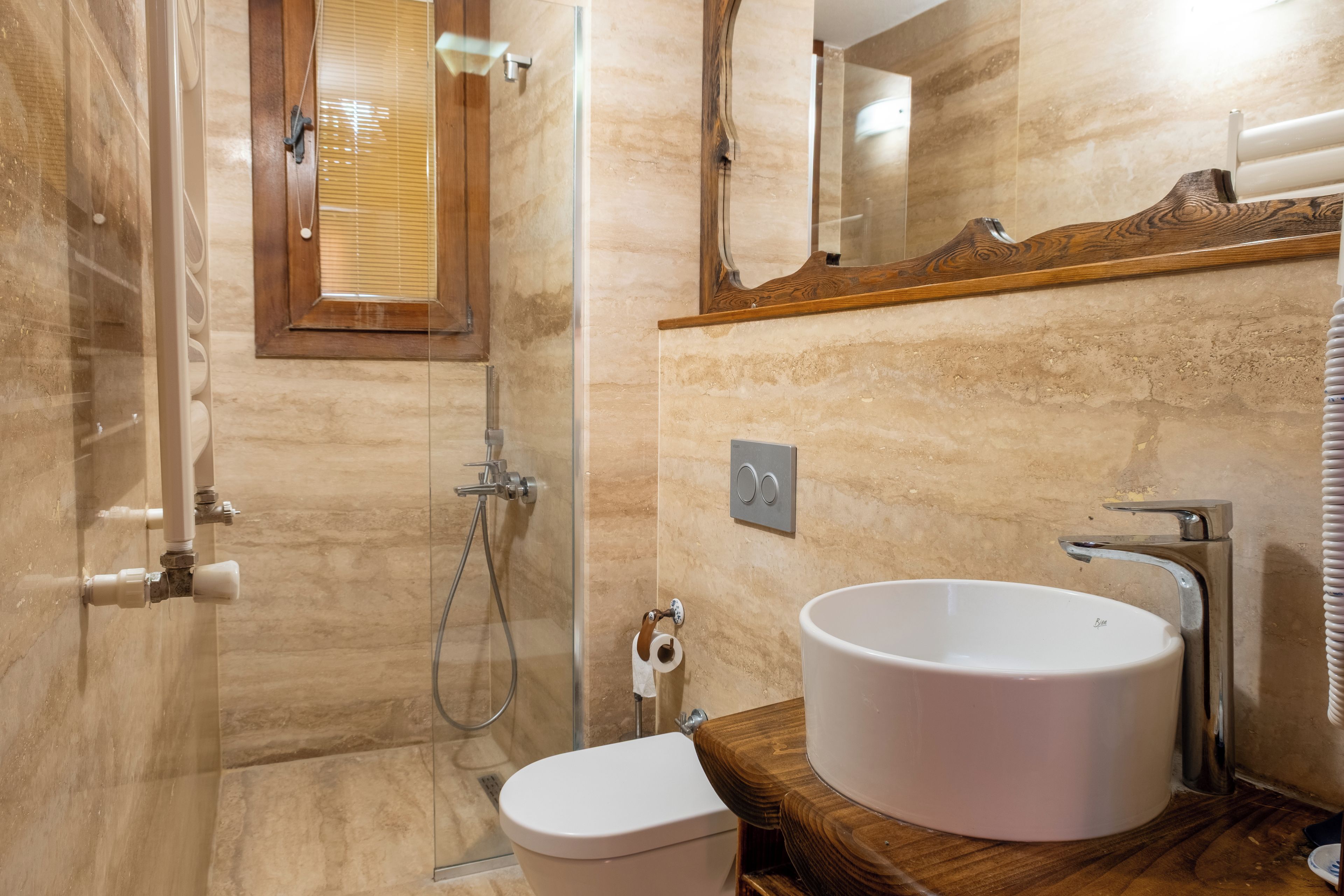 Une salle de bain avec une douche à parois de verre, un meuble-lavabo en bois et des toilettes.
