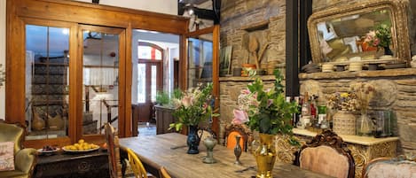 A dining area with a wooden table, chairs, and a stone wall.