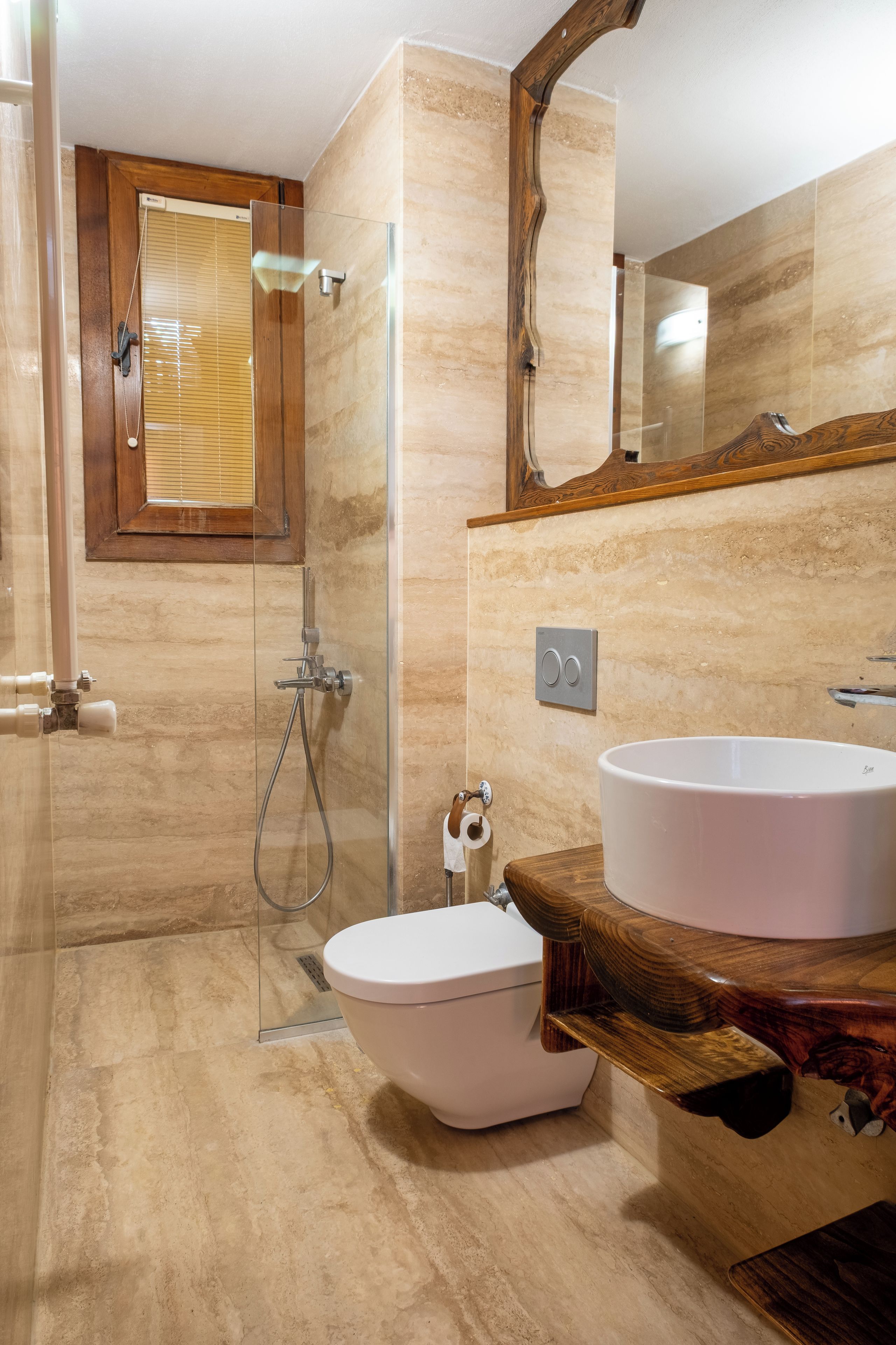 A modern bathroom with a glass-enclosed shower, a wooden vanity, and a large mirror.