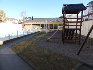 A backyard with a swimming pool, a wooden play structure, and a covered seating area. - Duplex del Sol (Villa Carlos Paz)