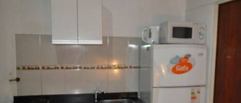 A compact kitchen with a gas stove, a sink, and a refrigerator with a Gafa logo.
