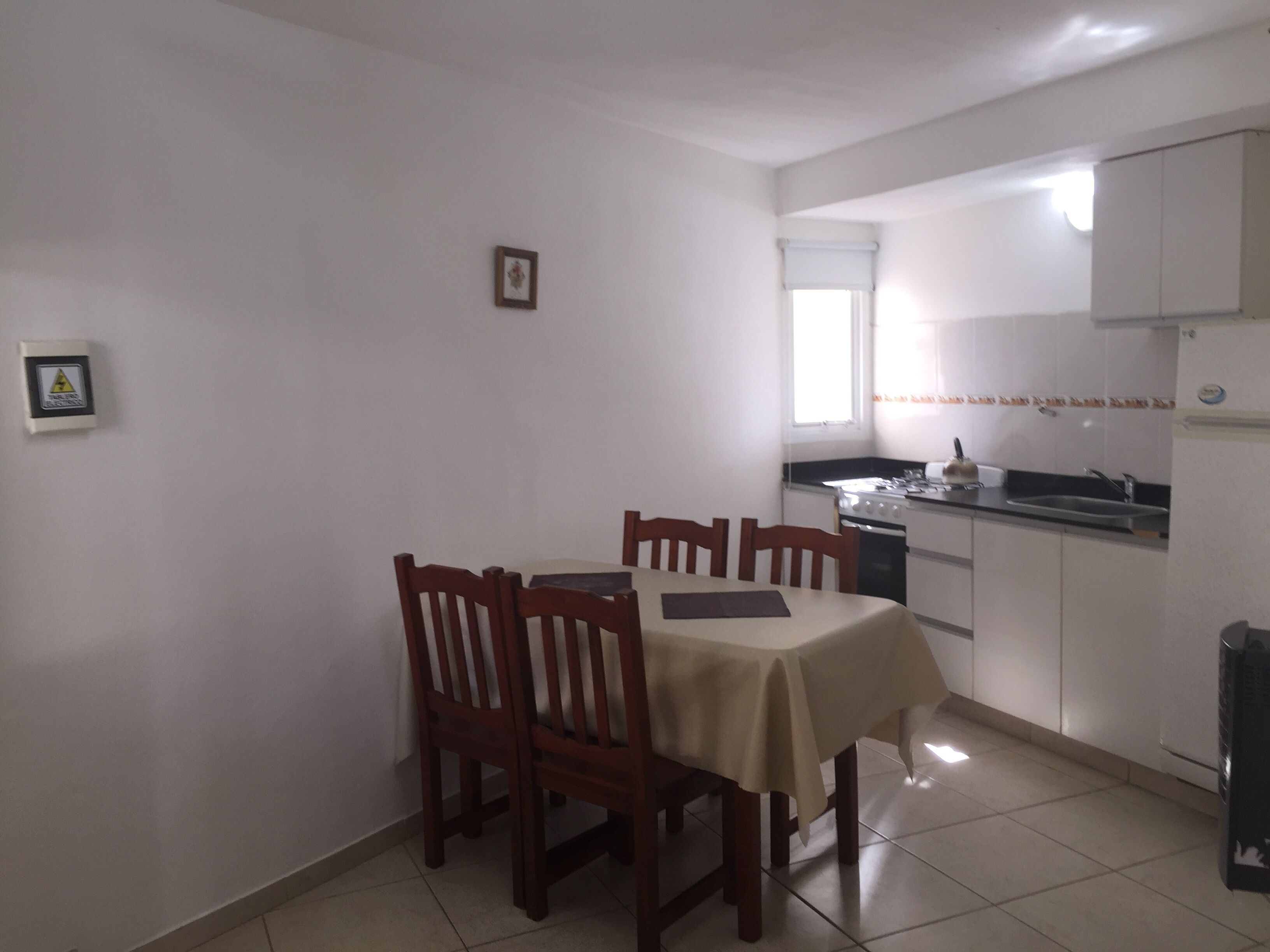 A compact kitchen with a dining table, chairs, and basic appliances.