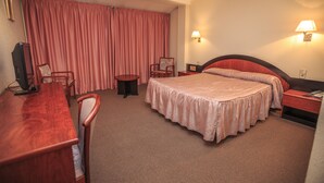 A hotel room with a bed, a desk, a chair, a small table, and a TV. - Hotel Roc del Castell (Canillo)
