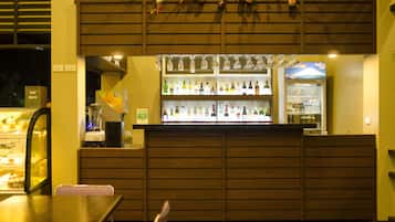 A bar area with a counter, shelves of bottles, and a display case.