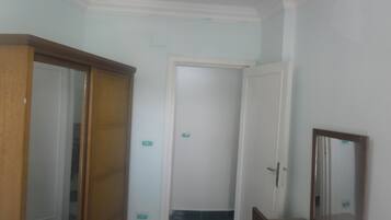 Een gang met een houten deur, een witte deur en een spiegel aan de muur.
