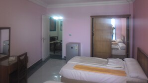 A hotel room with a bed, a desk, a chair, a mirror, and a door leading to another room. - Jewel Mandara Apartments (Alexandria)