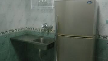A small kitchen with a sink, a refrigerator, and a wall-mounted shelf.