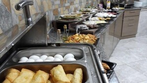 A buffet setup with various food items including fried items and eggs. - Mevlana Palace (Konya)