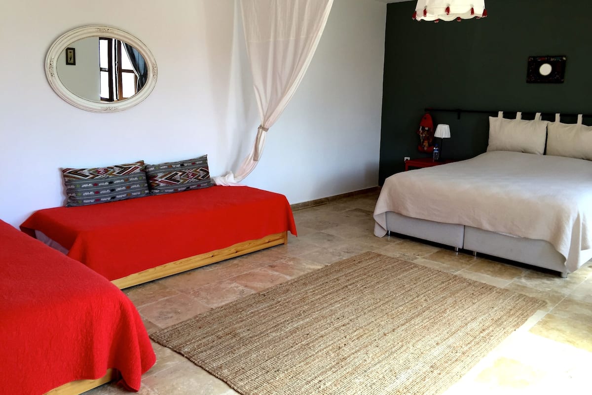 A bedroom with two beds, a mirror, a nightstand, and a hanging light fixture.