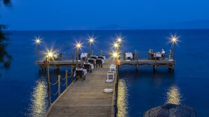 A wooden pier with tables and chairs set up for dining, extending into a calm body of water. - Orcey Hotel (Datça)