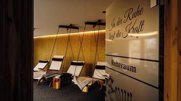 Een spa ruimte met loungestoelen, een massagetafel en een muur met tekst.