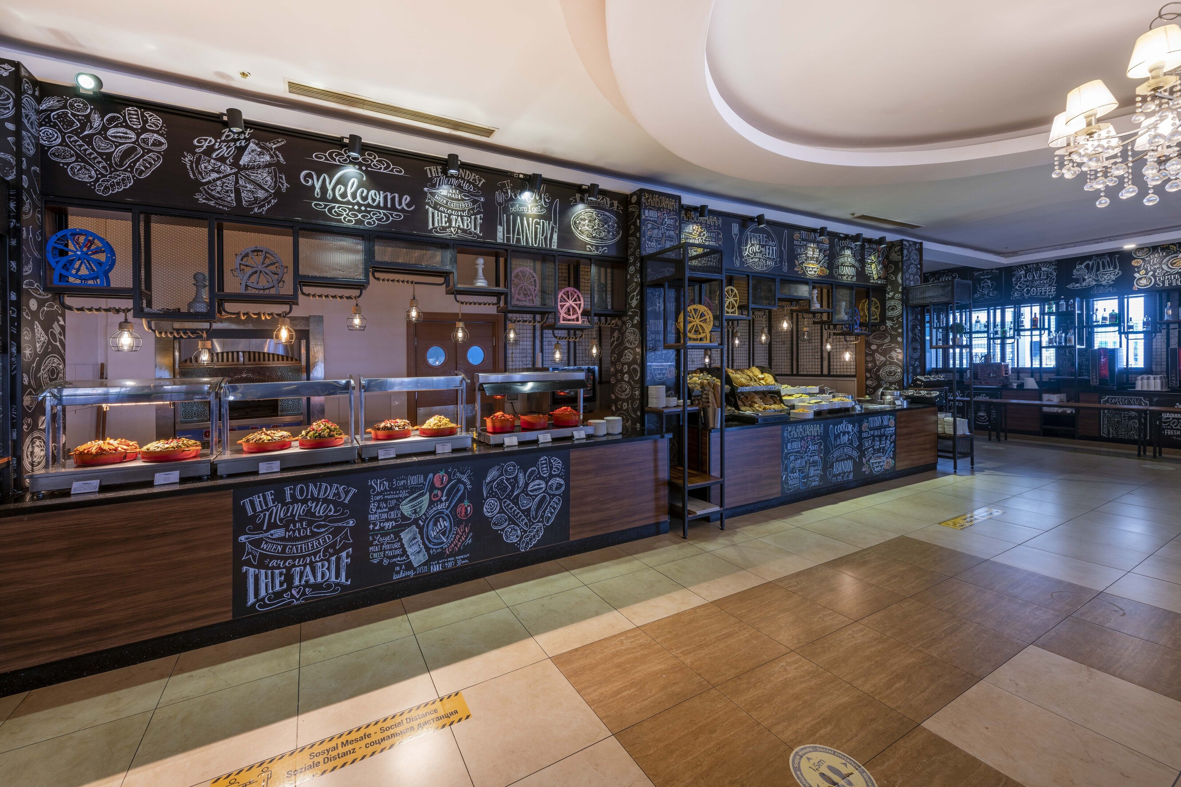A restaurant with chalkboard walls, a counter with food displays, and a chandelier.