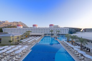 A hotel with a large swimming pool, multiple water towers, and a mountain backdrop. - Transatlantik Hotel & Spa -  Ultra All Inclusive (Kemer)