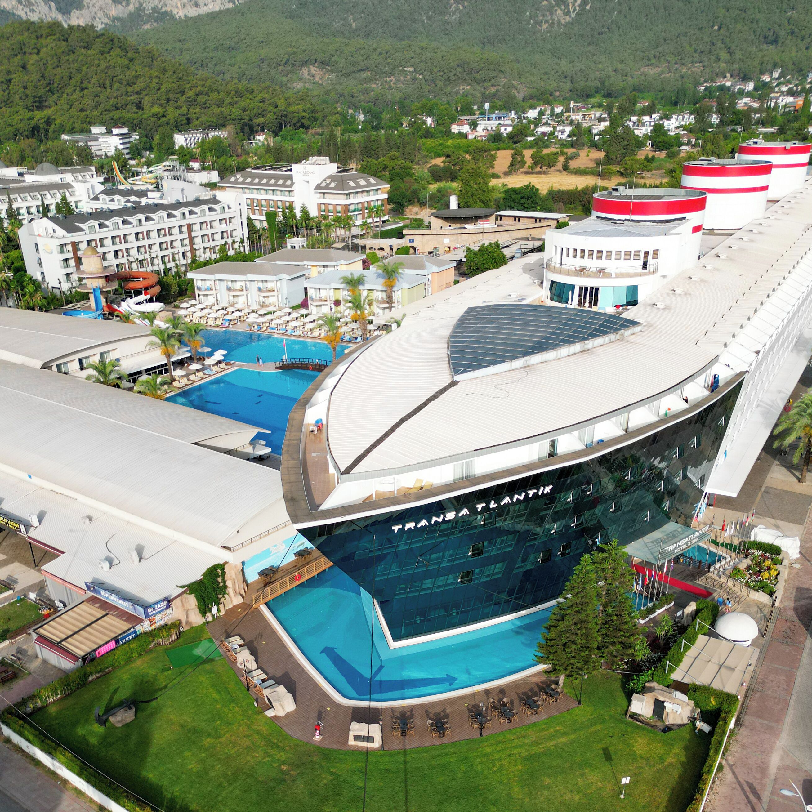 A modern hotel with multiple swimming pools, a large central pool, and a distinctive curved roof.