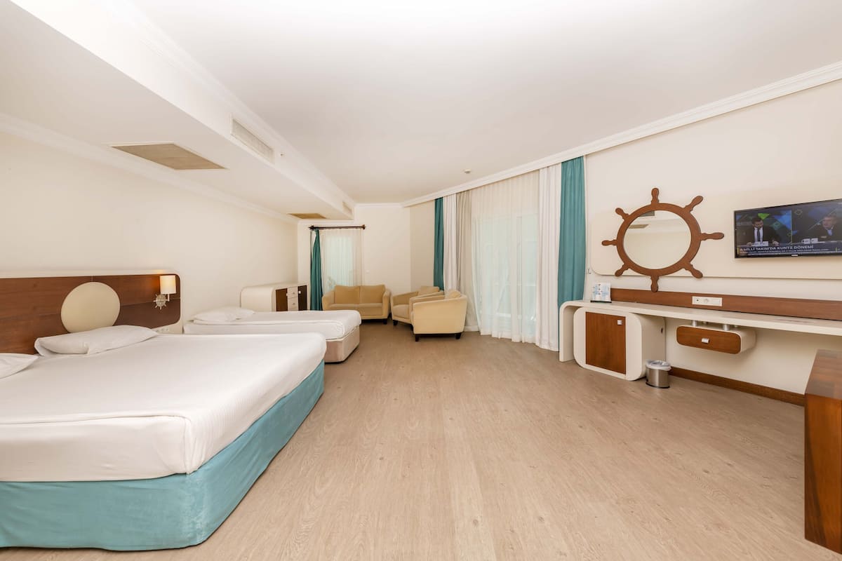 Ein Hotelzimmer mit zwei Betten, einem Schreibtisch mit Schiffslinienrad-Dekoration, einem Fernseher und einem Fenster mit Vorhängen.