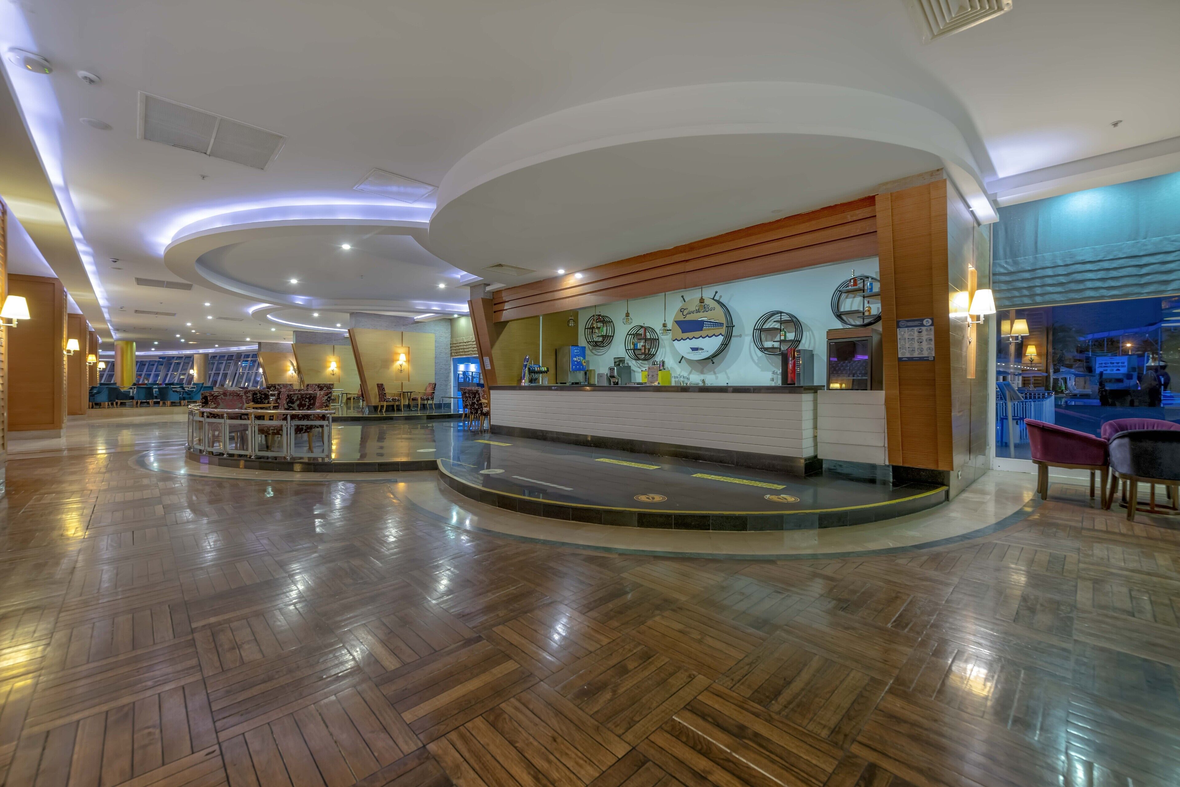 A spacious lobby with a wooden floor, a reception desk, and a seating area.