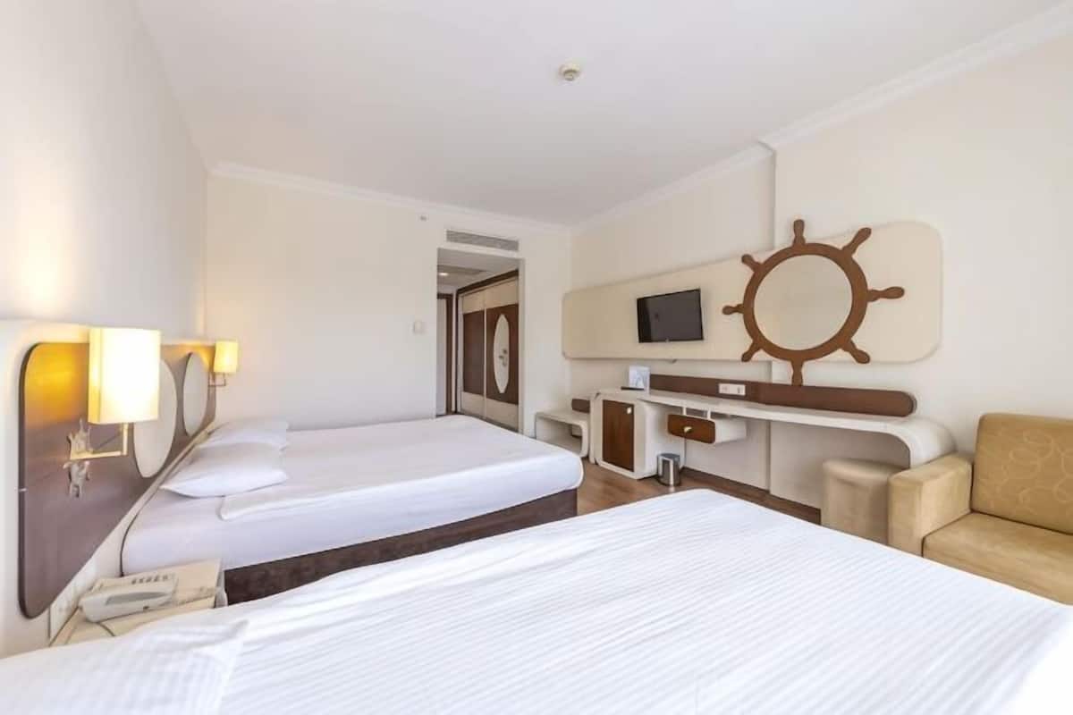 Ein Hotelzimmer mit zwei Betten, einem Schreibtisch mit Fernseher, einem Stuhl und einer Schiffslenkwellen-Dekoration.