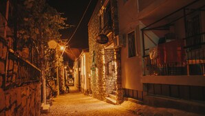 A narrow cobblestone street at night with stone buildings, a sign for 'PIRANTA', and a staircase leading to a second floor. - Pırlanta Butik Otel (Cesme)