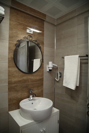 A bathroom with a white sink, a round mirror, a towel rack, and a handheld showerhead. - Pırlanta Butik Otel (Cesme)